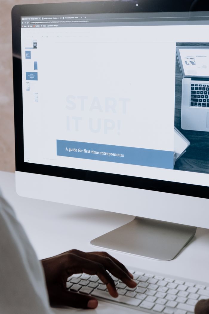 Mastering the First Impression: Your intriguing post title goes here Person working on a website design for first-time entrepreneurs on a desktop computer.